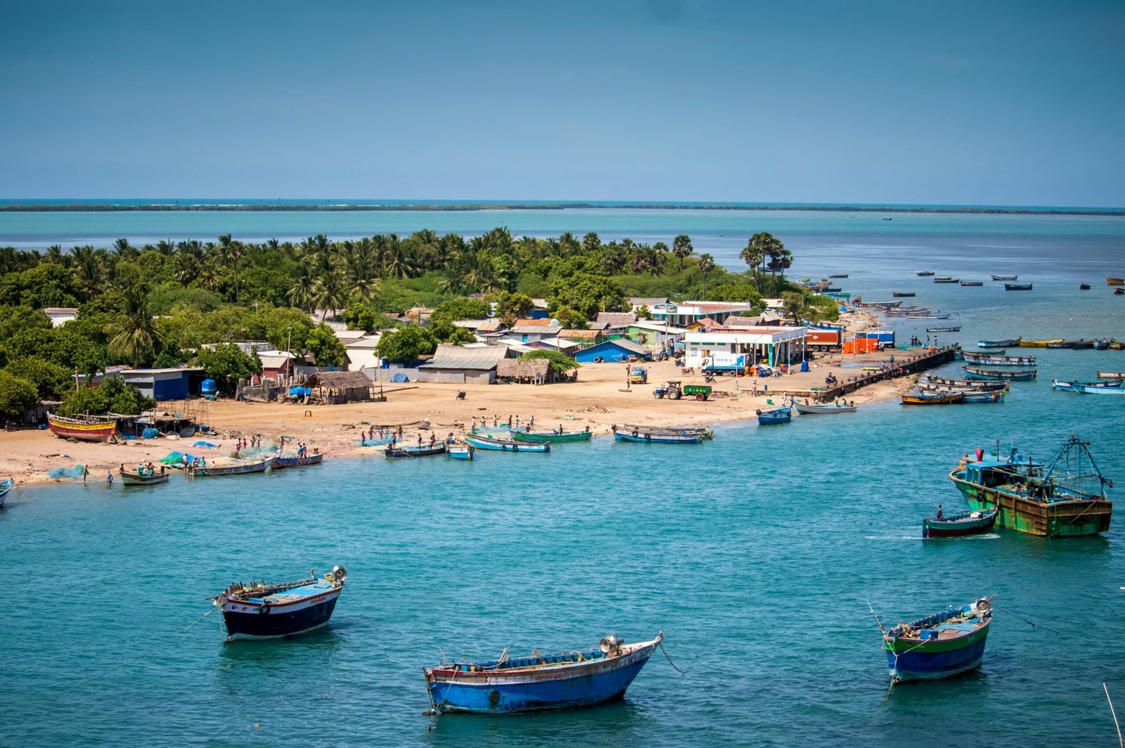 Dhanushkodi, TN, India beach with boats and palm trees viewed from above.