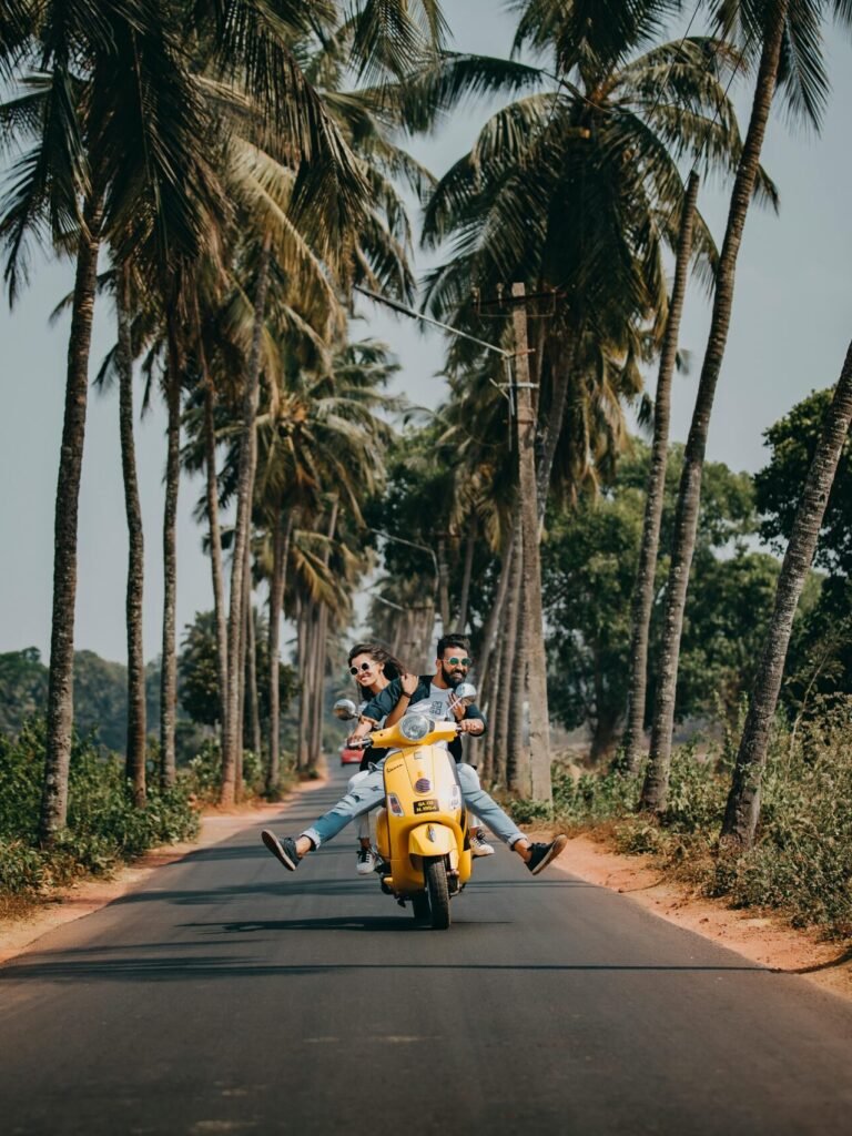 A joyful couple rides a yellow scooter through a scenic palm-lined road, capturing the essence of tropical travel and adventure.